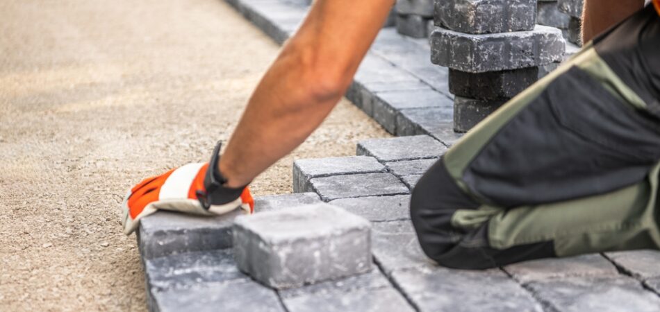 A,worker,carefully,positions,paving,stones,on,a,pathway,,focusing